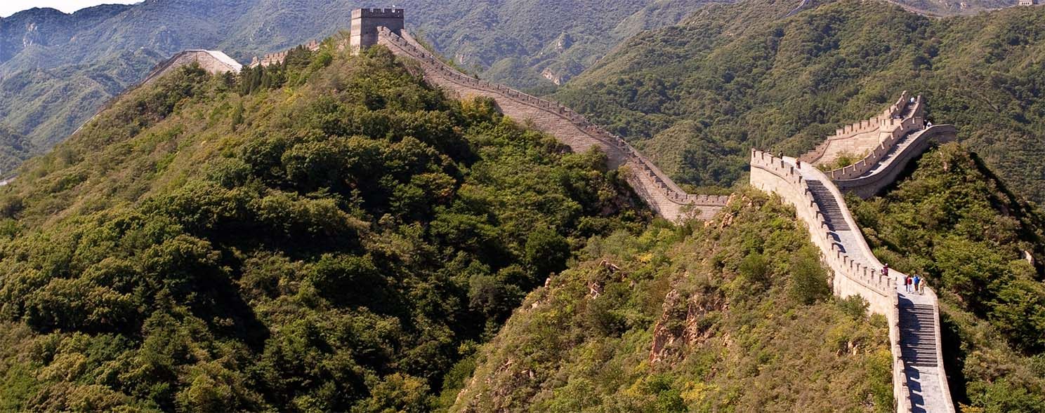 The Great Wall of China winding over green mountain ridges