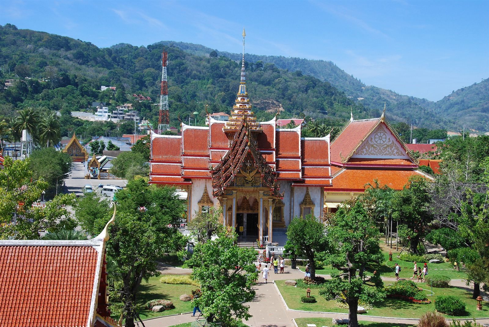 Red and gold temple roofs of Wat Chalong among gardens and hills, Phuket